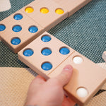 Close up of a hand moving a Bajo XXL wooden domino piece on a blue and white carpet