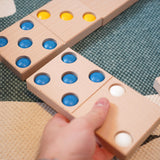 Close up of a hand moving a Bajo XXL wooden domino piece on a blue and white carpet