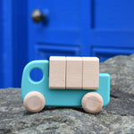 A light blue coloured Bajo truck with blocks placed on a stone wall 