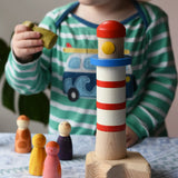 A child p[laying with the Bajo Lighthouse Stacker and Grapat Wild Crew wooden Nin peg dolls.