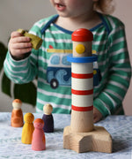 A child p[laying with the Bajo Lighthouse Stacker and Grapat Wild Crew wooden Nin peg dolls.