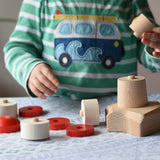 A child starting to assemble the Bajo Lighthouse Stacker all the pieces have been placed on a table.