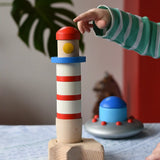 Child pointing at the Bajo wooden Lighthouse Stacker toy. The flying saucer is in the background. 