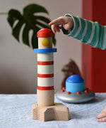 Child pointing at the Bajo wooden Lighthouse Stacker toy. The flying saucer is in the background. 