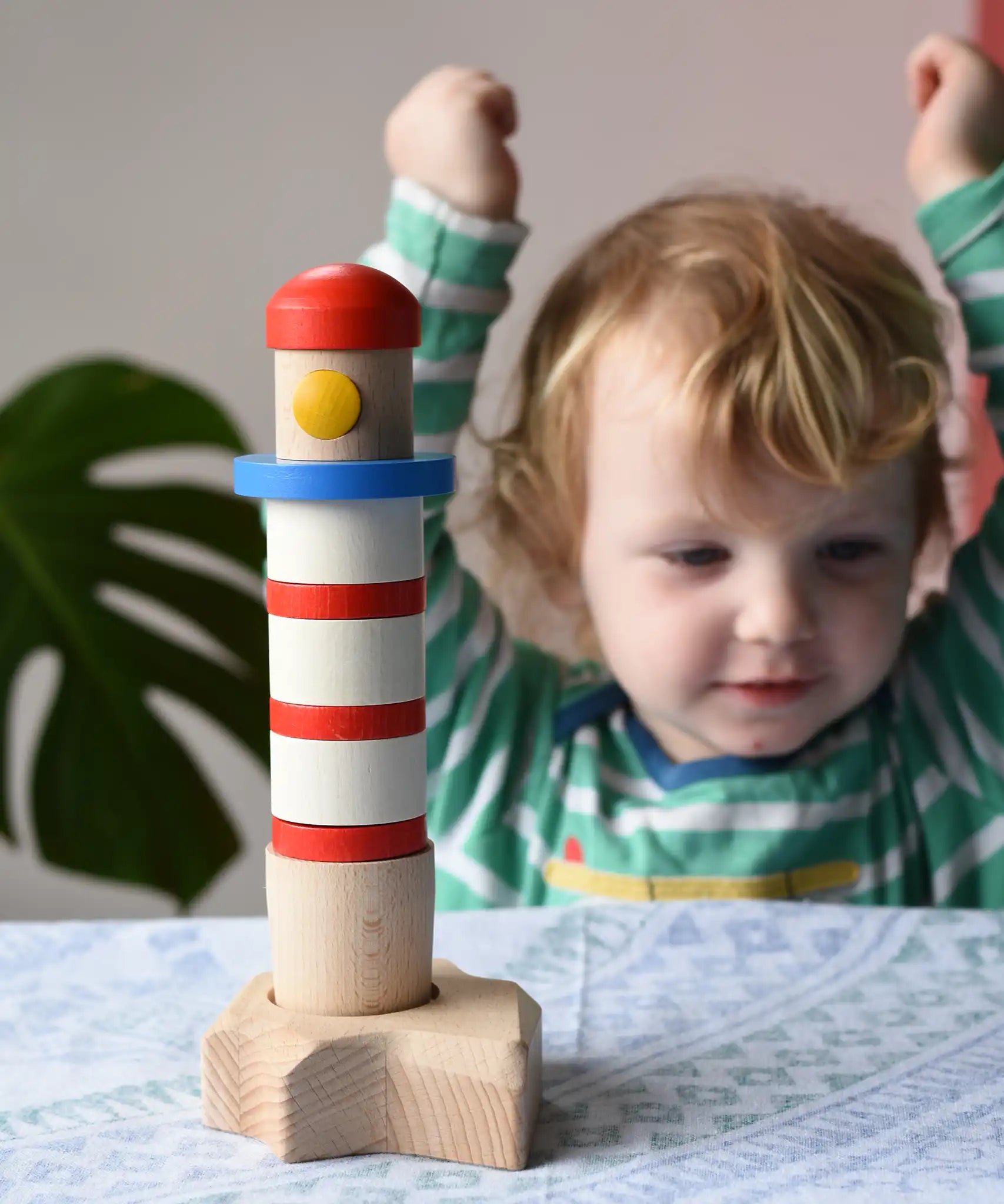 Child cheering at the Bajo Lighthouse Stacker placed on the table in front of them.