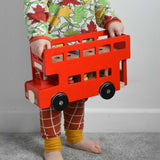 A child holding the Bajo Toys London bus toy in his hands. The roof has been taken off. These heirloom quality toys by Bajo are part of a wide range of wooden toys available here at Babipur. 