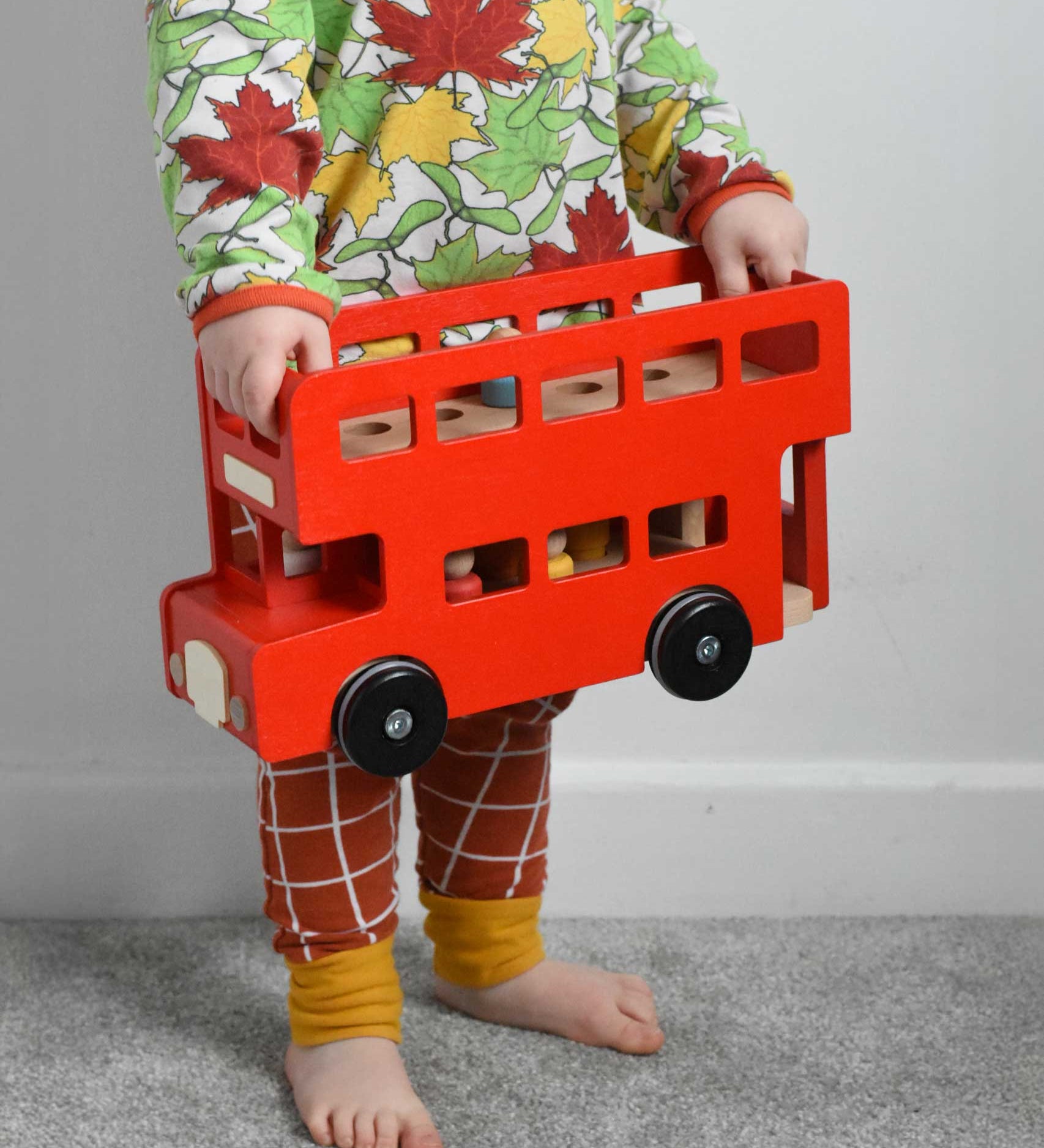 A child holding the Bajo Toys London bus  A red coloured wooden double decker bus wooden toy in his hands. The roof has been taken off. These heirloom quality toys by Bajo are part of a wide range of wooden toys available here at Babipur. 
