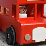 A close up of the  bus driver peg doll from the Bajo London bus wooden toy sitting in the driver's spot on the bus.  These heirloom quality toys by Bajo are part of a wide range of wooden toys available here at Babipur.