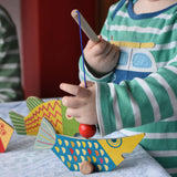 Bajo magnetic fishing game toy. Child holding wooden rod placing it onto blue fish.