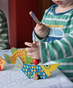 Bajo magnetic fishing game toy. Child holding wooden rod placing it onto blue fish.