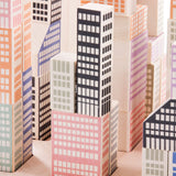 A close up of the Bajo Manhattan city Blocks wooden toy blocks on a wooden base.