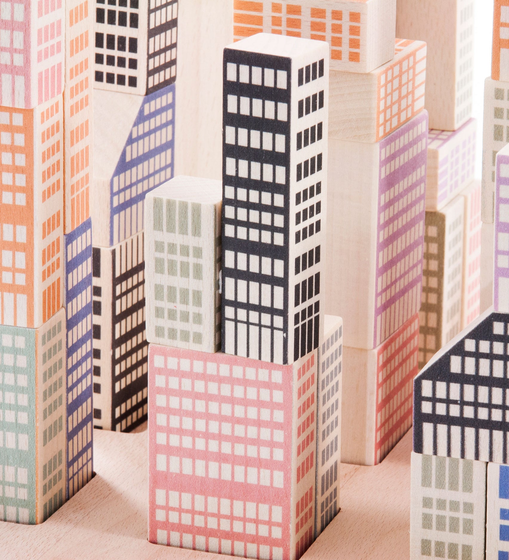 A close up of the Bajo Manhattan city Blocks wooden toy blocks on a wooden base.