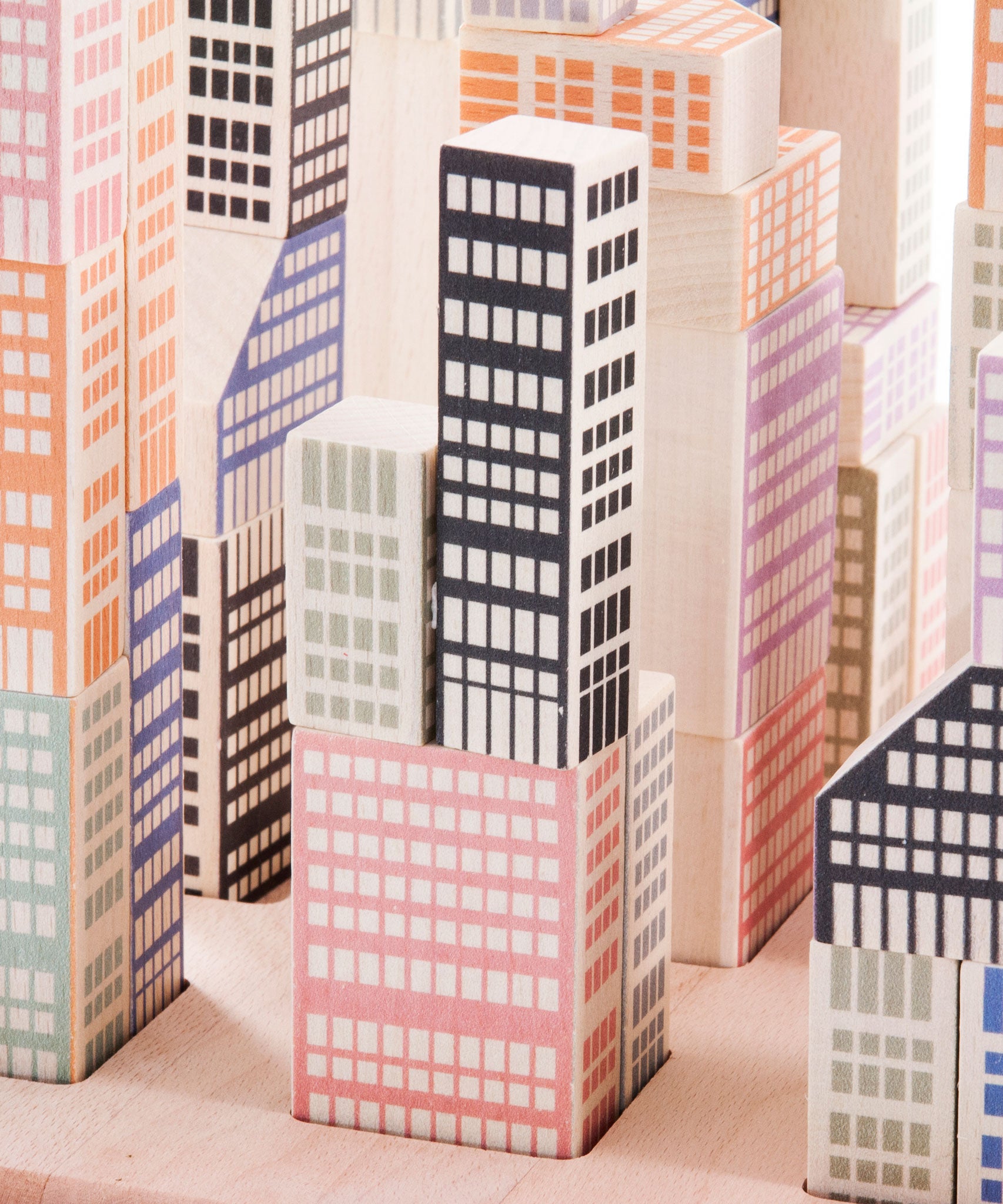 A close up of the Bajo Manhattan city Blocks wooden toy blocks on a wooden base.