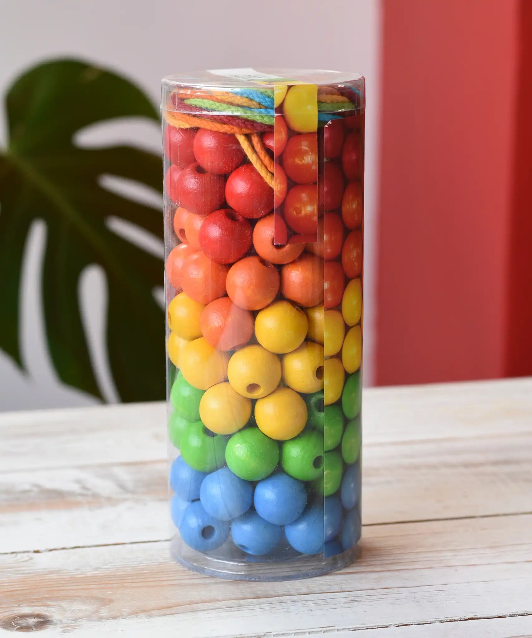 Bajo Mathematical Threading Beads Game in it's packaging placed on a white wooden surface. 