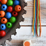 Close up of the 5 coloured threads, dice and beads included in the Bajo Mathematical Threading Beads Game.