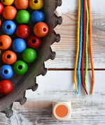 Close up of the 5 coloured threads, dice and beads included in the Bajo Mathematical Threading Beads Game.