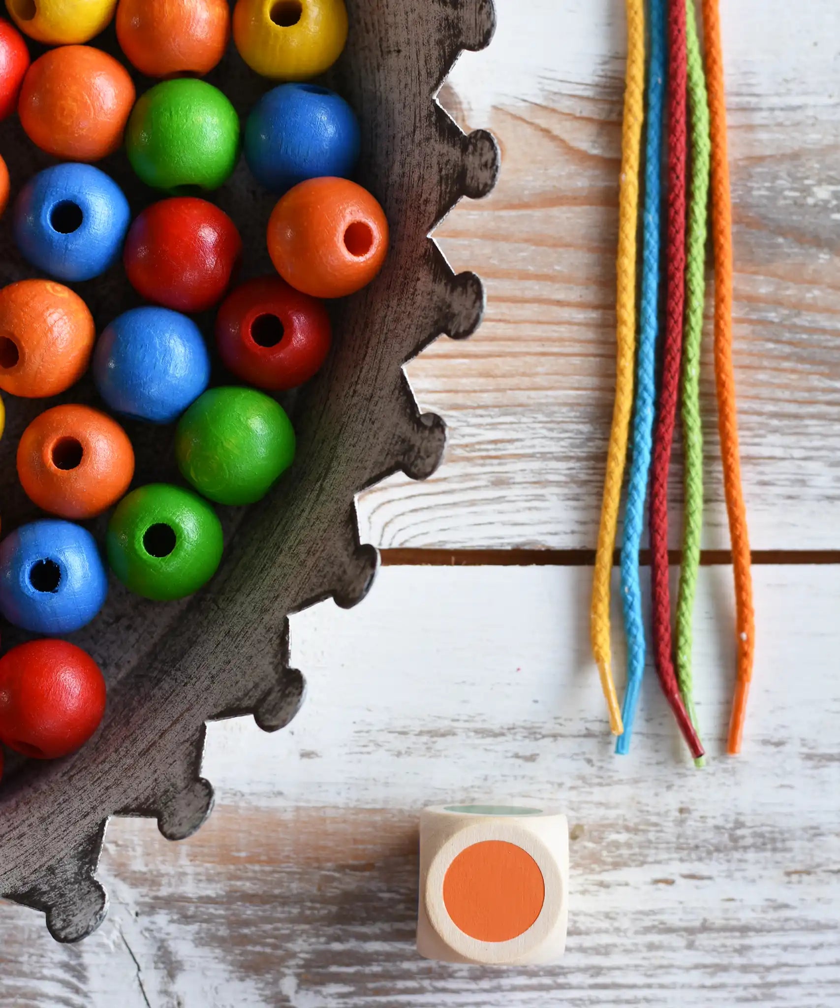 Close up of the 5 coloured threads, dice and beads included in the Bajo Mathematical Threading Beads Game.