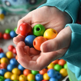Close up of wooden beads from the Bajo Mathematical Threading Beads Game in a child's hand.
