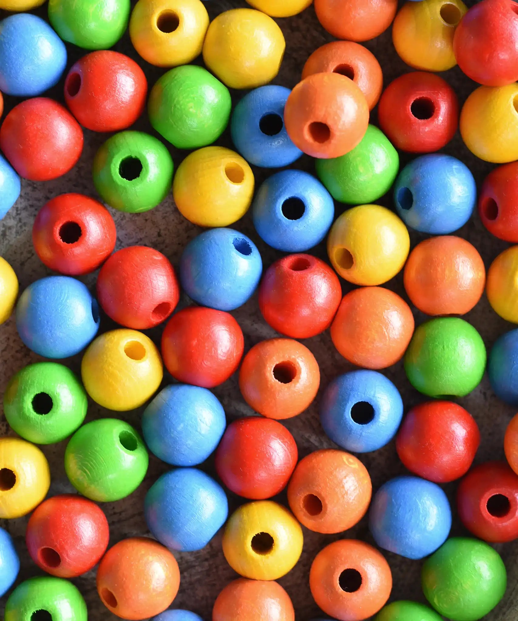 Close up of the  red, orange, yellow, green and blue beads from the Bajo Mathematical Threading Beads Game