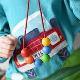 A child holding up a thread with 6 wooden beads on from the Bajo Mathematical Threading Beads Game.