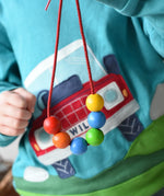 A child holding up a thread with 6 wooden beads on from the Bajo Mathematical Threading Beads Game.