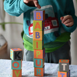 Child playing with the Bajo Me & You Alphabet Blocks placing the blocks on top of each other. 