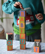 Child playing with the Bajo Me & You Alphabet Blocks placing the blocks on top of each other. 