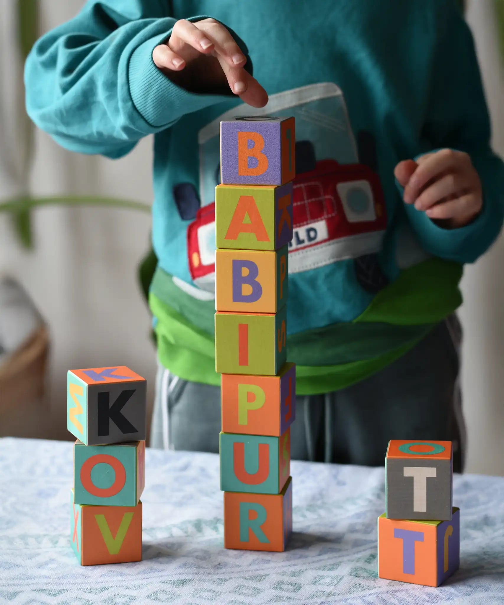 Child playing with the Bajo Me & You Alphabet Blocks placing the blocks on top of each other. 