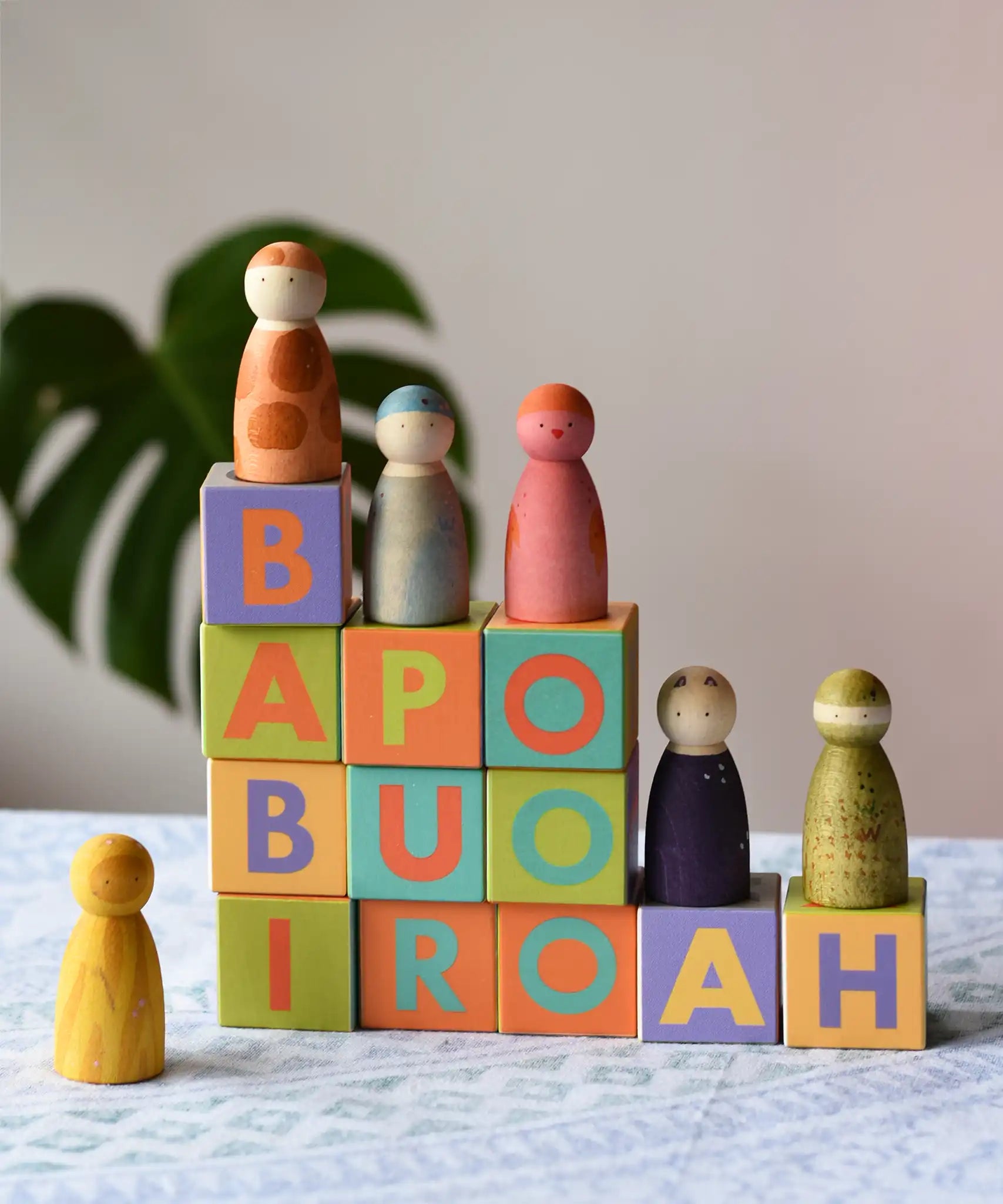 Bajo Me & You Alphabet Blocks with Grapat Wild crew wooden Nin peg dolls placed on top of them.