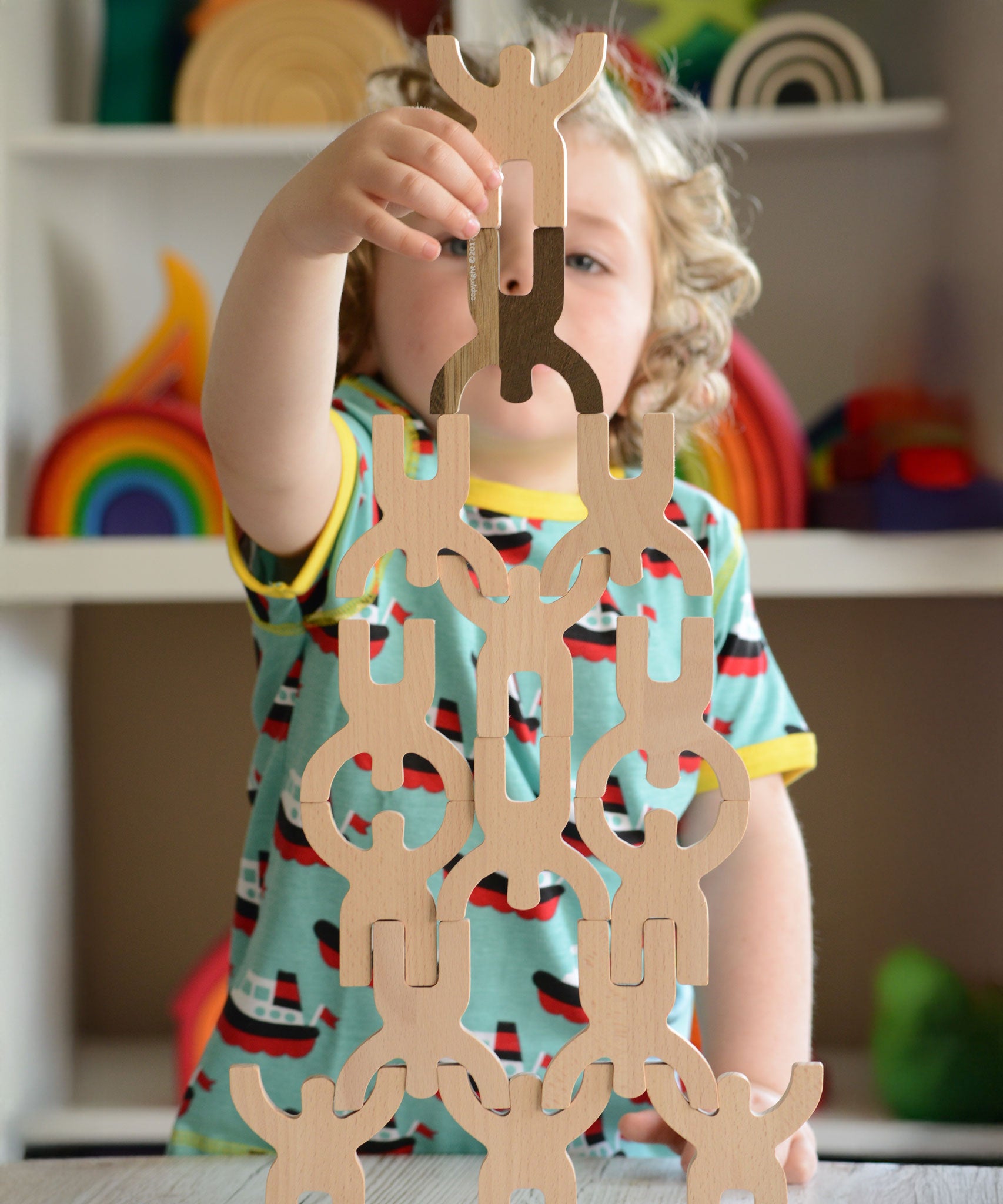 A child playing with the Bajo Mendelsons wooden Balancing Game. A set of 15 wooden figures that can be balanced in various ways.