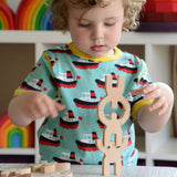 A child playing with the Bajo Mendelsons wooden Balancing Game. A set of 15 wooden figures that can be balanced in various ways.
