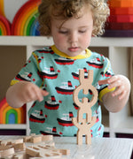 A child playing with the Bajo Mendelsons wooden Balancing Game. A set of 15 wooden figures that can be balanced in various ways.