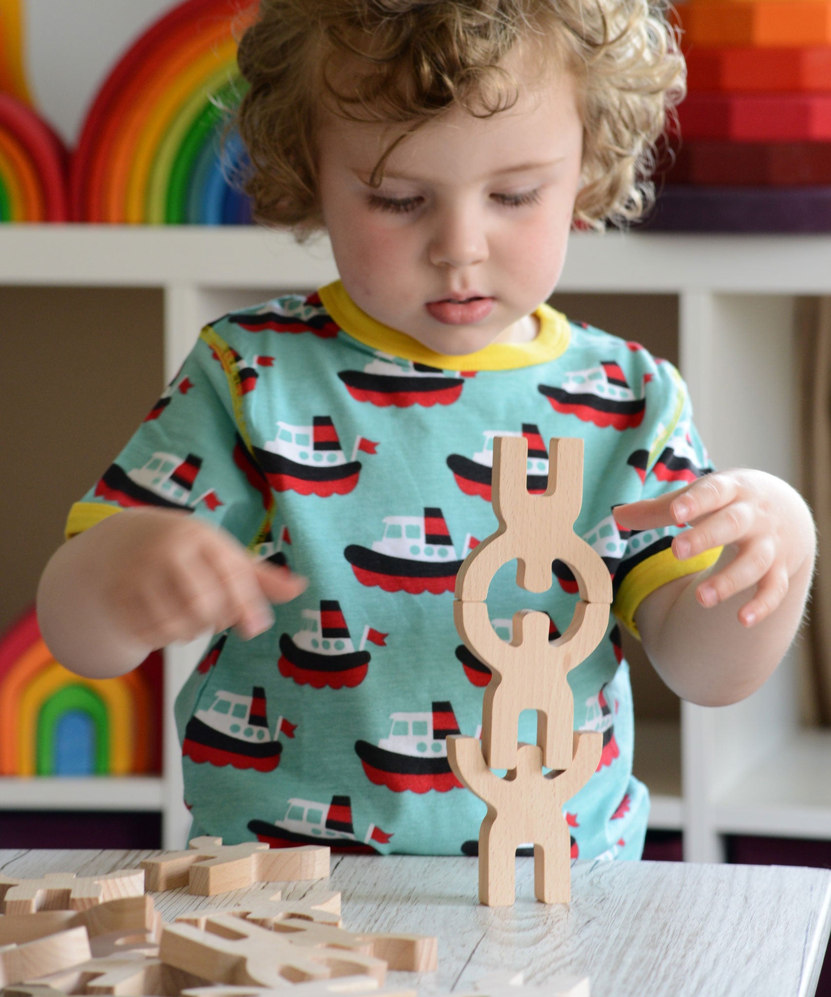 A child playing with the Bajo Mendelsons wooden Balancing Game. A set of 15 wooden figures that can be balanced in various ways.
