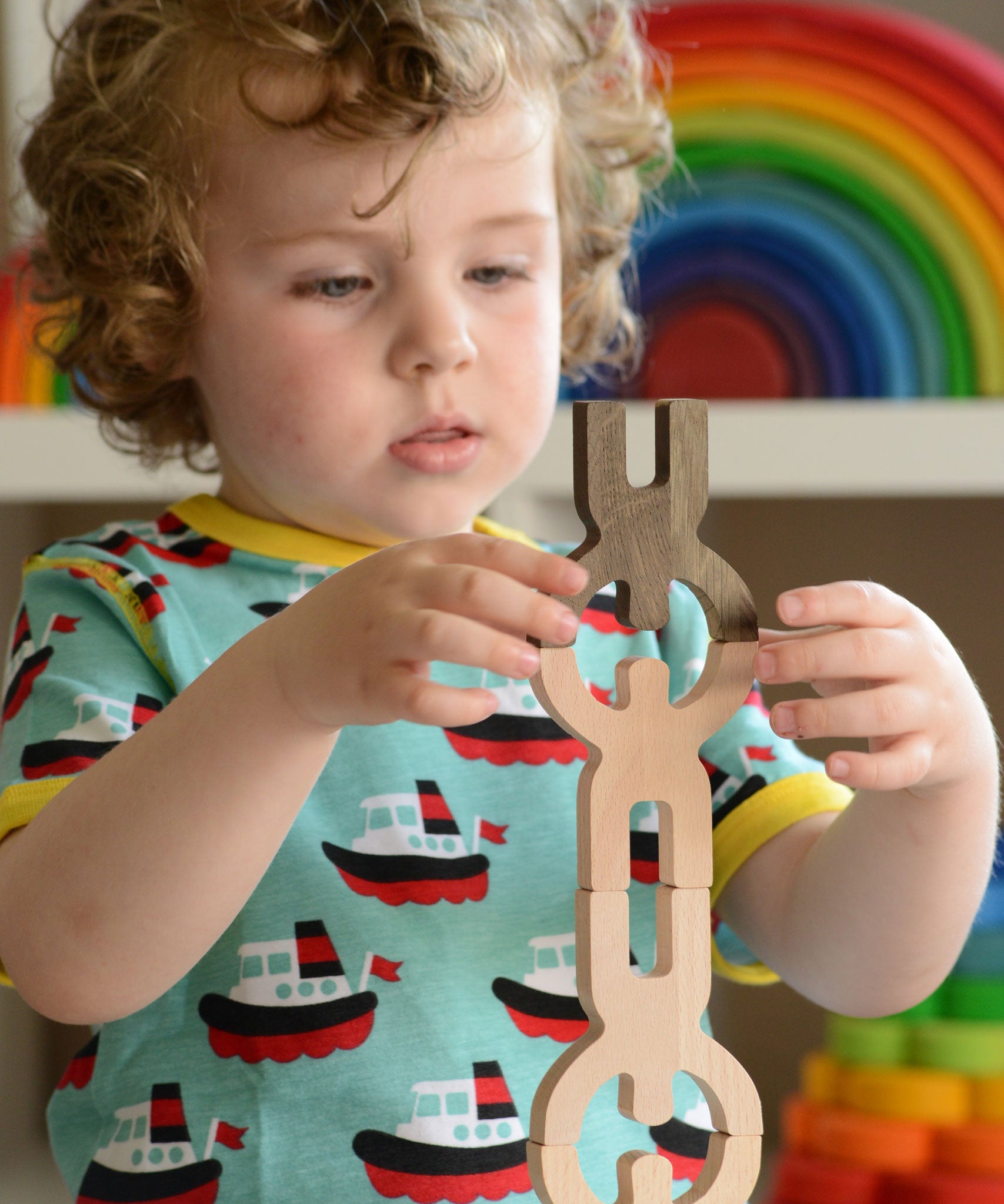A close up of a child playing with the Bajo Mendelsons wooden Balancing Game. A set of 15 wooden figures that can be balanced in various ways.