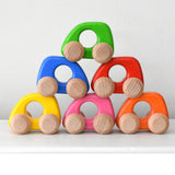 Colorful wooden toy cars stacked on top of each other form Bajo toys