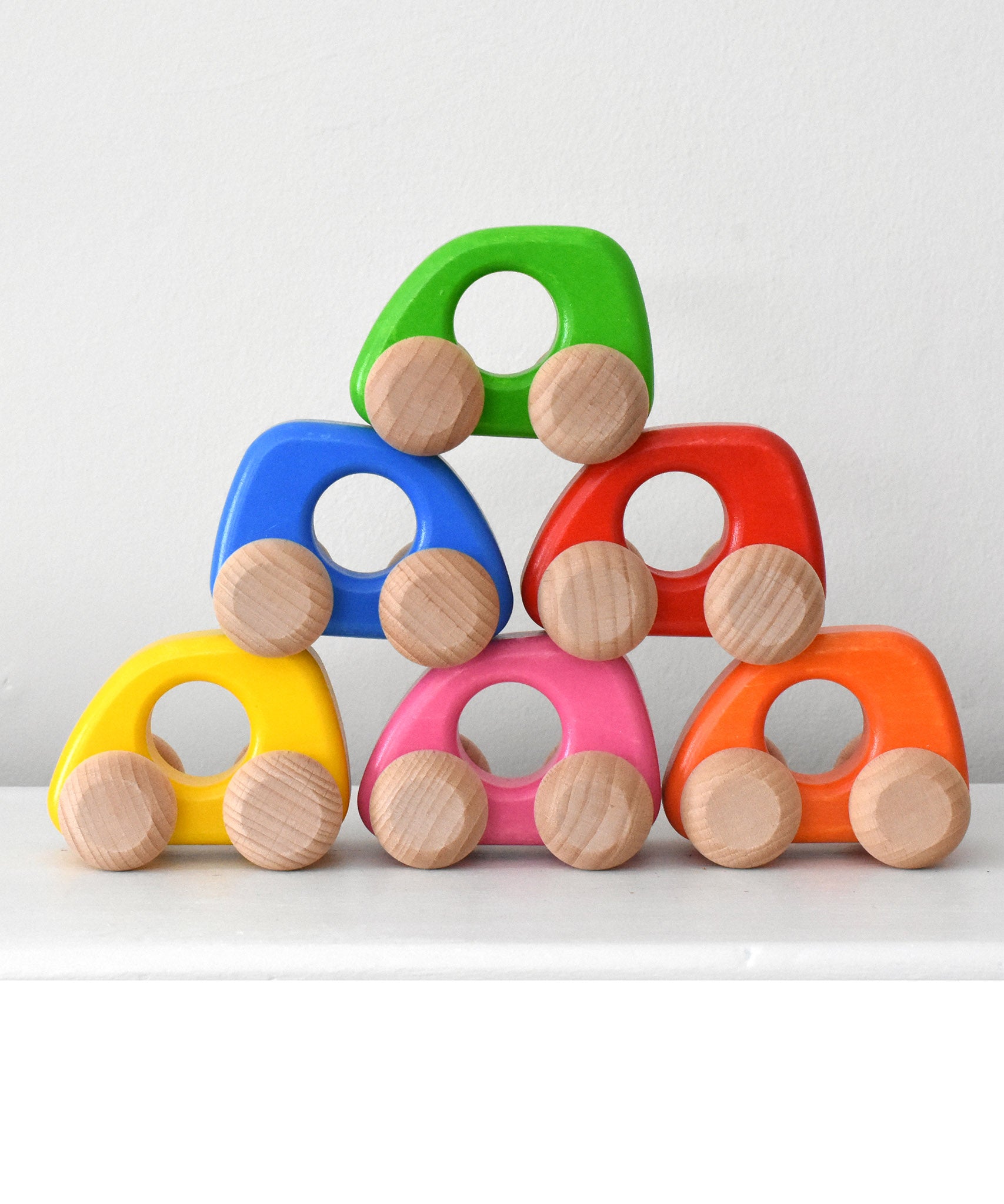 Colorful wooden toy cars stacked on top of each other form Bajo toys