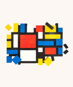 Bajo toys wooden Mondrian Building Blocks used to create a modern pattern. A mix of black, white, yellow, red and blue coloured blocks in a box with square and rectangular shaped blocks.