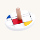 Bajo Mondrian Spinning Top. A white painted spinning top decorated with black, blue, red and yellow line designs.