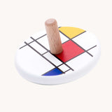 Bajo Mondrian Spinning Top. A white painted spinning top decorated with black, blue, red and yellow line designs.