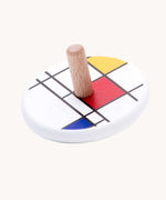 Bajo Mondrian Spinning Top. A white painted spinning top decorated with black, blue, red and yellow line designs.