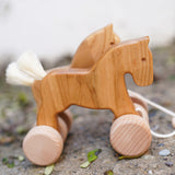 Bajo hand made wooden natural jumping horse available at Babipur. Features unpainted wheels and. Horses are standing on a stone surface