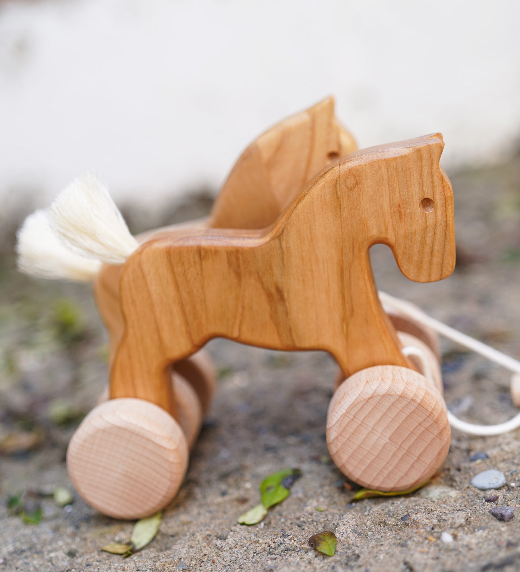 Bajo hand made wooden natural jumping horse available at Babipur. Features unpainted wheels and. Horses are standing on a stone surface