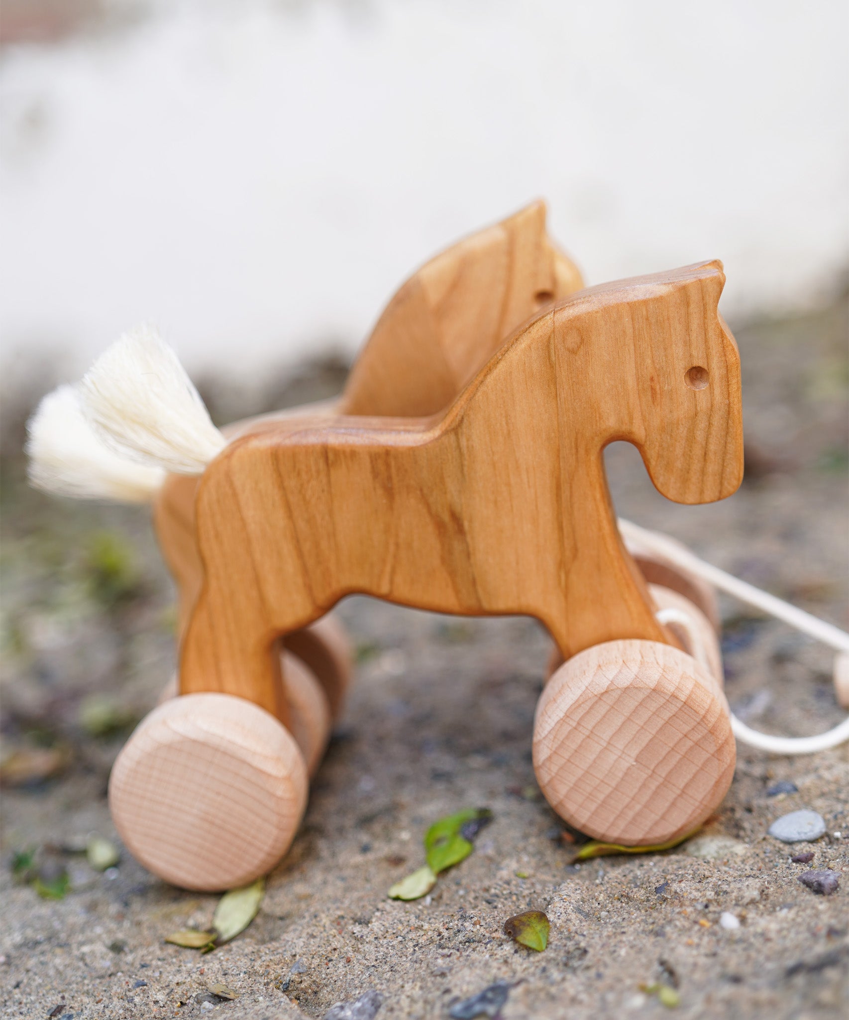 Bajo hand made wooden natural jumping horse available at Babipur. Features unpainted wheels and. Horses are standing on a stone surface