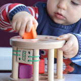 A close up of a child slotting an orange coloured wooden piece into the snail sorter. These heirloom quality toys by Bajo are part of a wide range of wooden toys available here at Babipur. 