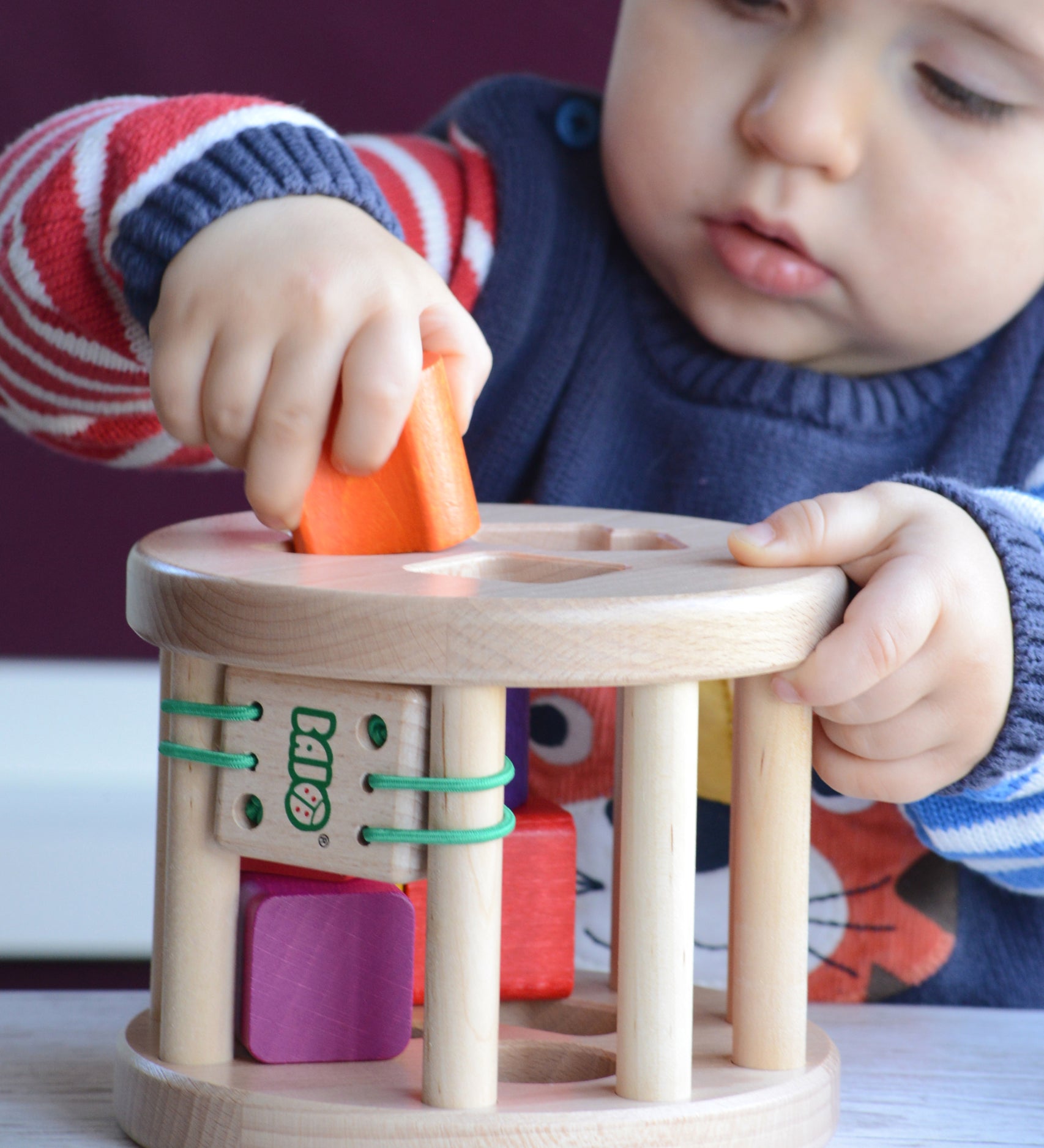 A close up of a child slotting an orange coloured wooden piece into the snail sorter. These heirloom quality toys by Bajo are part of a wide range of wooden toys available here at Babipur. 