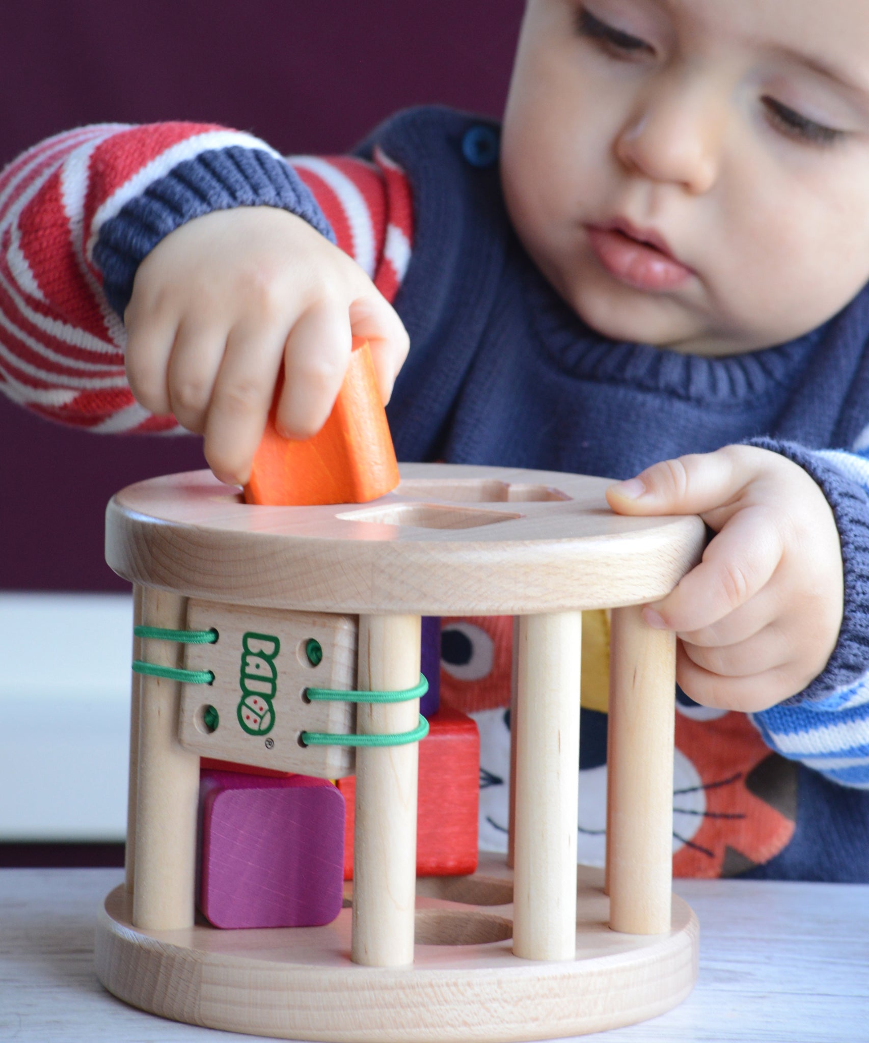A close up of a child slotting an orange coloured wooden piece into the snail sorter. These heirloom quality toys by Bajo are part of a wide range of wooden toys available here at Babipur. 