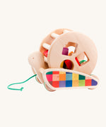 Bajo Natural Snail Sort Roller. A circular shaped wooden roller with coloured shapes that slot through the shaped holes on the side sitting on a pull-along snail. These heirloom quality toys by Bajo are part of a wide range of wooden toys available here at Babipur. 