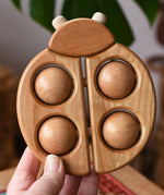 Bajo natural wooden ladybird teether shown in an adult's hand in the Babipur playroom.