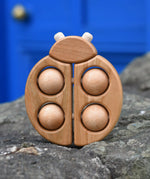 Bajo natural wooden ladybird teether placed on a stone wall outdoors in the Babipur garden.