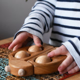 Child rolling the moveable balls on the Bajo natural wooden ladybird teether in the Babipur playroom.